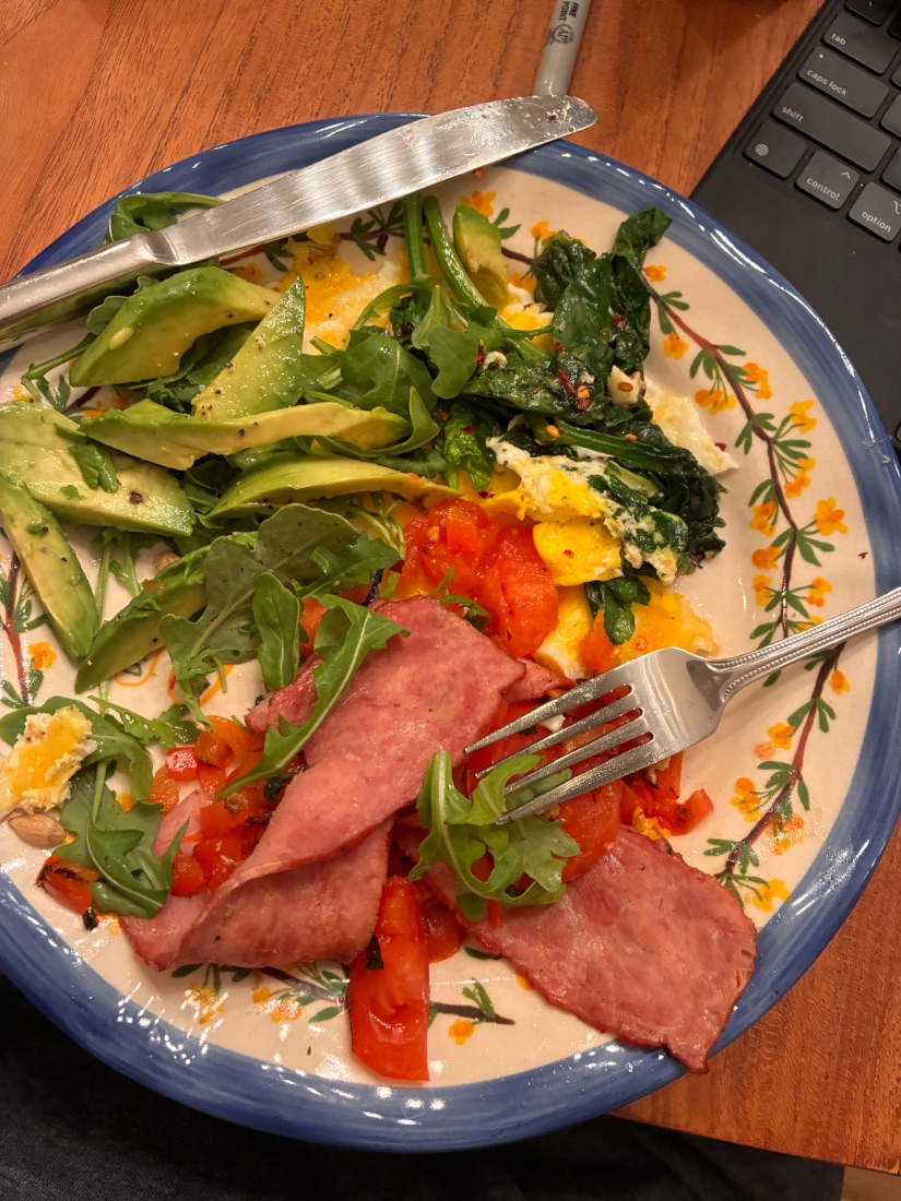 Eggs, avocado, greens and turkey bacon on a blue patterned plate