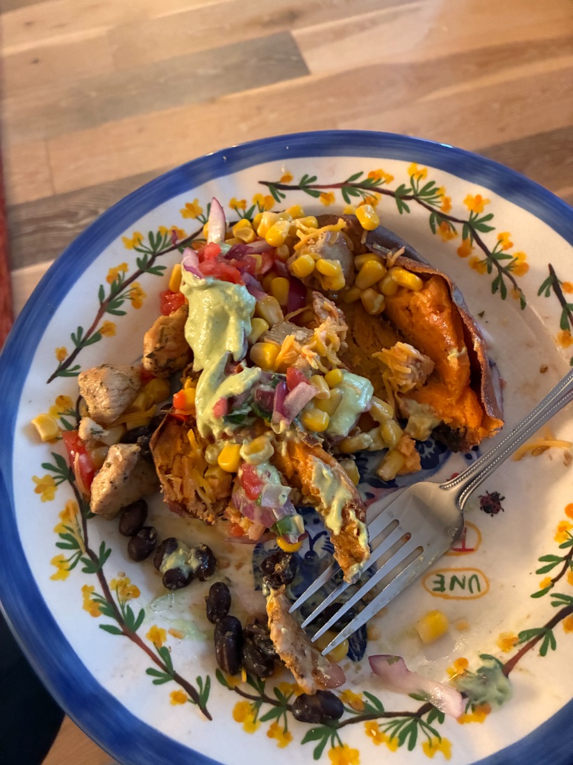A loaded sweet potato with black beans, corn and salsa