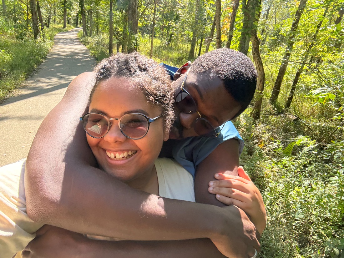 Nicole and her husband Timothy hugging on a trail, smiling